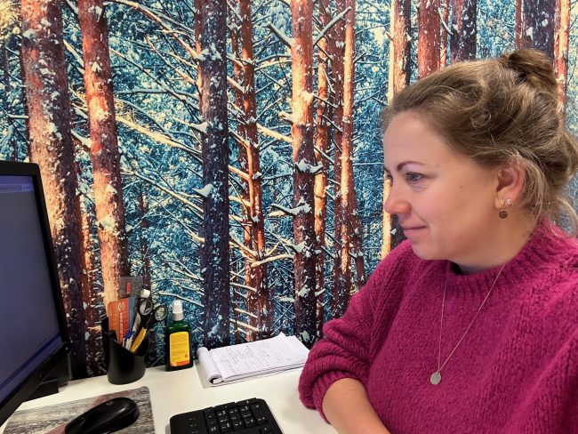 Marjolein Wind Ergotherapeut Marjolein Wind zit aan een bureau en kijkt naar het scherm van een computer.