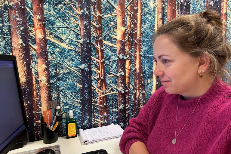 Marjolein Wind Ergotherapeut Marjolein Wind zit aan een bureau en kijkt naar het scherm van een computer.